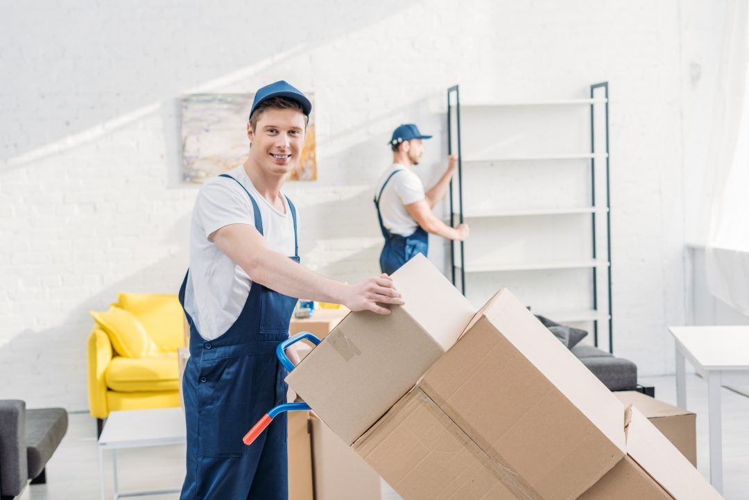 Zwei Umzugshelfer im Transport von Kartons und Möbeln in Wohnung
